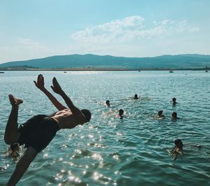 People swimming in sea against sky