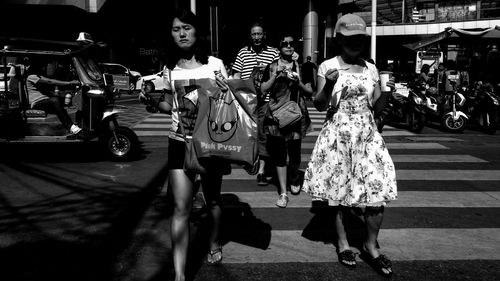 Rear view of people walking on street in city