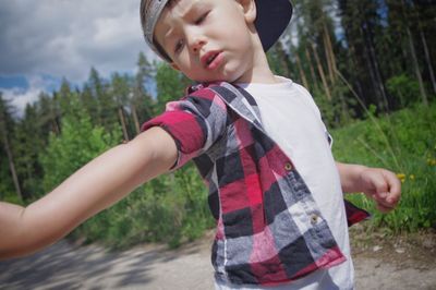 Boy looking away while standing by plants