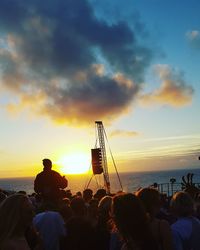 Silhouette people at beach against sky during sunset