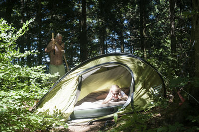 Girl relaxing in tent by man in forest