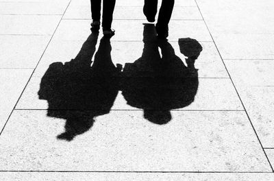 Low section of people walking on footpath during sunny day