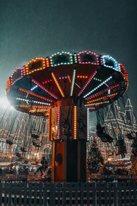 Winter season in the night. glowing festive carousel whirling on the street under the flying snow.