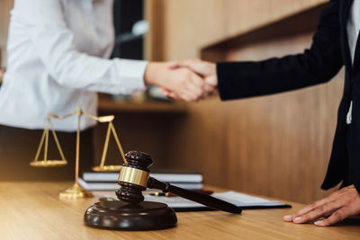 Cropped image of judge shaking hands with client on table