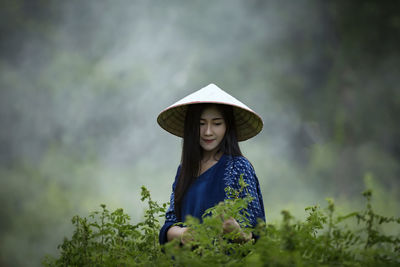 Young woman wearing asian style conical hat on field