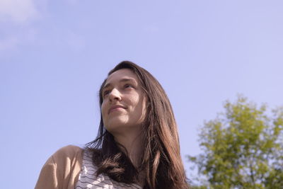 Young woman looking away against sky