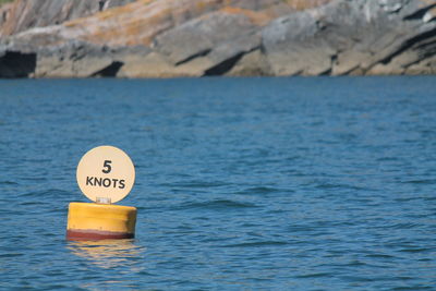 Close-up of yellow sign by sea