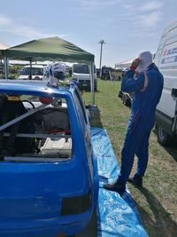 Side view of man standing by car on road