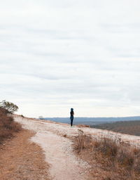 Rear view of man walking on beach against sky