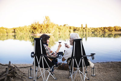 Senior couple clinking wine glasses at a lake in the evening