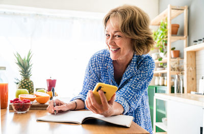 Young woman using mobile phone while sitting at home