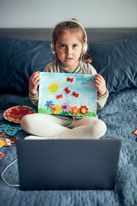 Portrait of girl having a video call sitting on bed at home