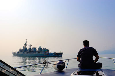 Rear view of man looking at sea against clear sky