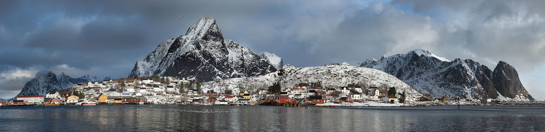 Panoramic view of frozen lake and buildings against sky