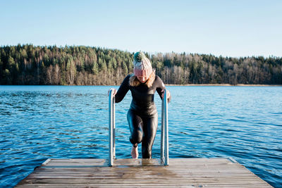 Woman climbing out of the water in winter from cold water swimming
