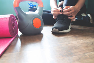 Low section of woman tying shoelace on floor