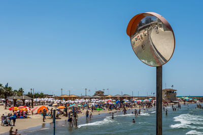 People on beach against clear blue sky