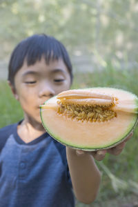 Close-up of boy holding melon outdoors