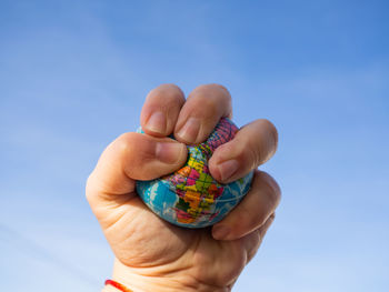 Close-up of person holding hands against blue sky