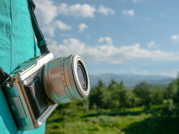 Close-up of camera on landscape against sky