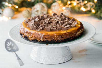 A whole chocolate caramel cheesecake on a pedestal stand ready to be cut into.