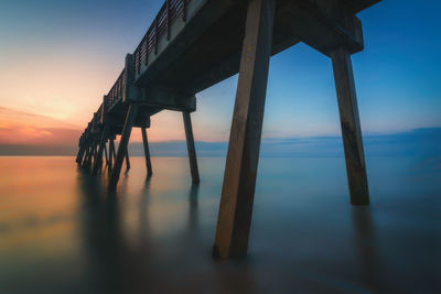 Pier over sea against sky during sunset