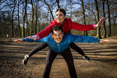 Young couple is playing happy in the woods during a workout. 