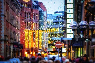 Crowd on illuminated city street at night
