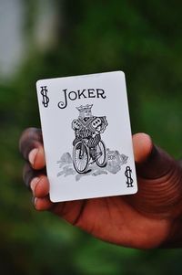 Cropped hand of man showing joker card