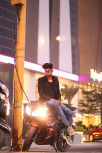 Young man sitting at illuminated night