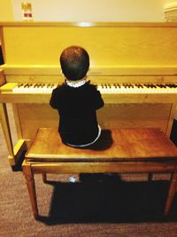 Rear view of boy playing piano
