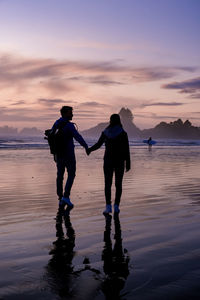 People on beach against sky during sunset