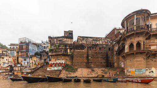 Boats moored in canal against buildings in city