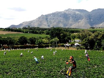 People relaxing in farm against sky