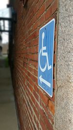 Close-up of road sign against brick wall