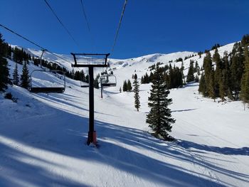 Ski lift on snow covered mountain against clear sky