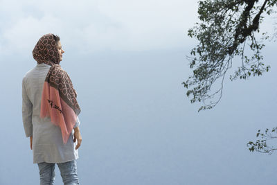 Rear viewpoint of a young muslim woman enjoying in the misty -fogy weather