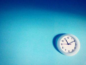 Low angle view of clock on blue wall