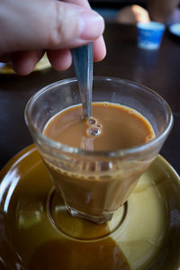 Close-up of hand pouring tea in glass