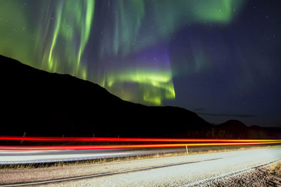 Light trails on road against sky at night
