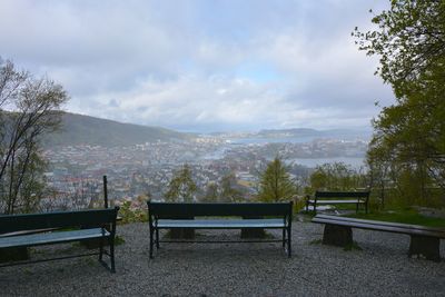 Empty bench in park against sky