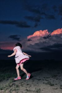 Full length of girl playing on field against cloudy sky at dusk