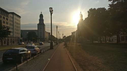 City street amidst buildings against sky during sunset