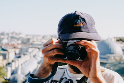 Portrait of man photographing camera against sky