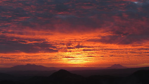 Scenic view of mountains against cloudy sky at sunset