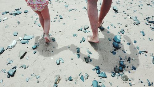 Low section of people walking on beach