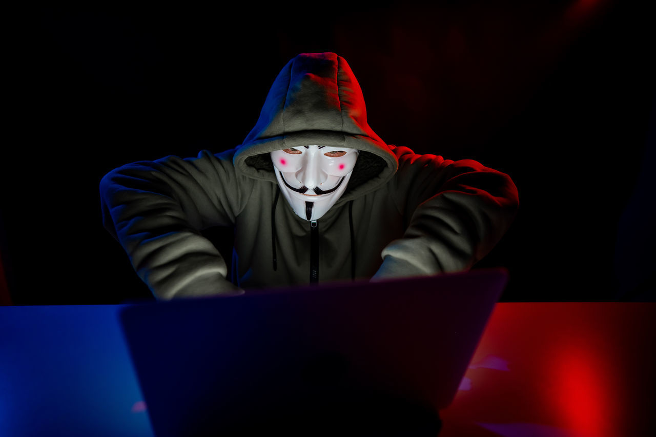 one person, laptop, adult, front view, computer, men, communication, disguise, mask, indoors, clothing, dark, mask - disguise, screenshot, technology, portrait, obscured face, red, business