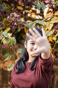 Portrait of young woman against leaves