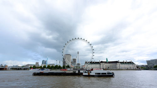Ferris wheel in city against cloudy sky
