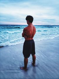 Shirtless man standing at beach